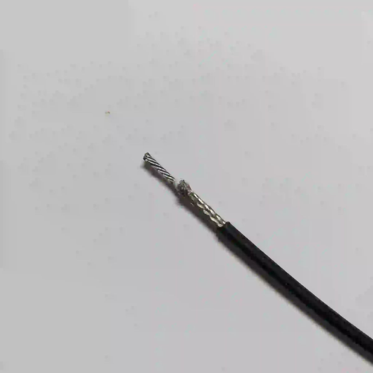 A black A2B cable with the end stripped to show a braided metallic shield and a stranded wire core.