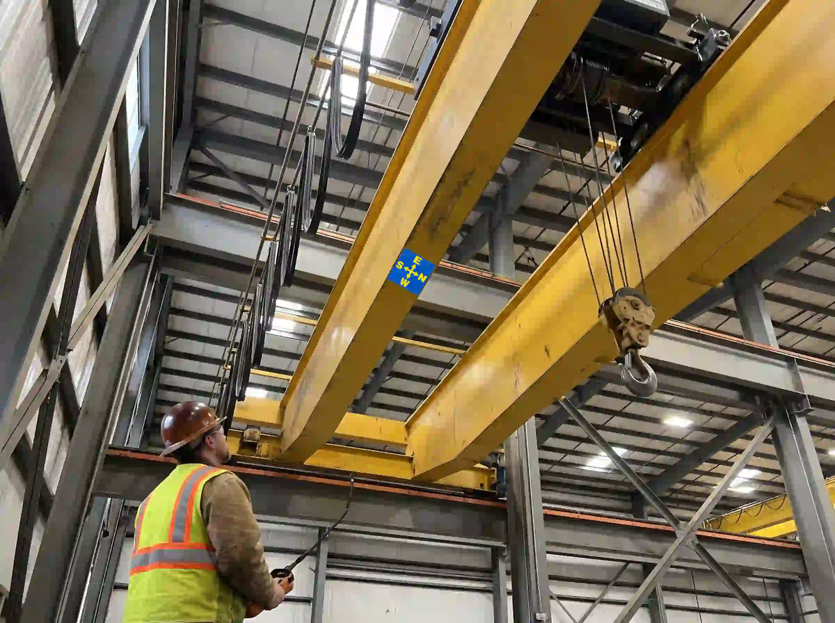 AI-generated illustration of an operator looking up at a DIR-013 directional decal mounted on an overhead crane beam’s underside.